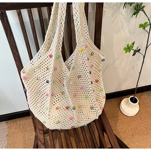 Detailed close-up of beige crochet tote bag with colorful beads on a wooden chair