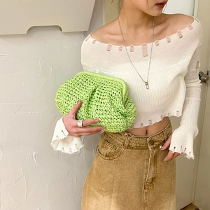 Chic light green straw woven clutch bag paired with a stylish beach outfit and denim skirt