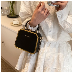 Detail of black octagonal box bag with gold metal trim and chain shoulder strap