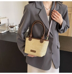 Detail of a beige straw tote bag with brown leather trim and FASHION & BAGS leather patch