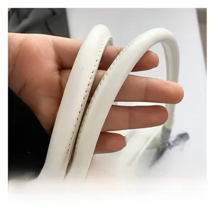 Detail of the white bow handbag handle with fine stitching and cylindrical design