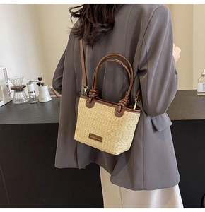 Detail of straw woven bucket bag with brown leather trim and crossbody strap on model
