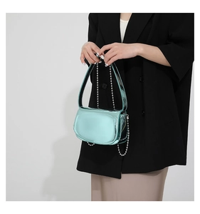 Detail of mint green patent leather bag featuring silver bead trim and metal chain strap