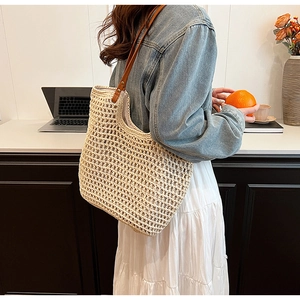 Detail of hand-woven beige tote bag with premium brown leather straps and metal rivets