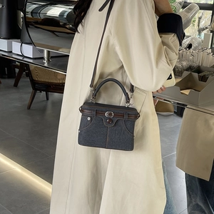 Chic dark gray denim crossbody bag with brown leather straps and metal buckle details
