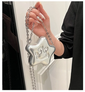 Detail of silver star-shaped Y2K crossbody bag featuring a debossed smiley face and metal chain