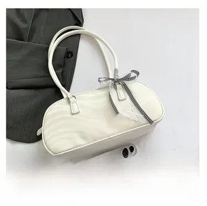 Detail of cream white pillow bag featuring wavy textured PU leather and a bow decoration