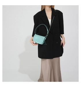 Detail of light blue patent leather handbag with silver chain and curved top handle