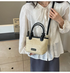 Detail of straw woven texture and black leather straps on a stylish bucket shoulder bag
