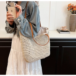 Detail of hand-woven mesh tote bag with brown leather straps and beige cotton lining