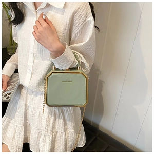 Detail of light green hexagonal box bag with gold metal trim and chain strap for women