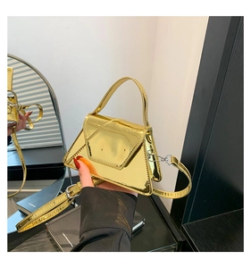 Close-up of golden mirror finish trapezoid bag with metallic texture and sleek handle