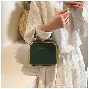 Detailed view of dark green box bag with gold metal frame and twisted top handle