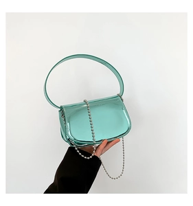 Close-up of mint green patent leather handbag with silver ball chain and wide handle