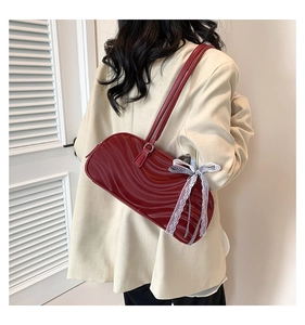 Detail of dark red wavy texture handbag with lace and checkered bow on beige suit