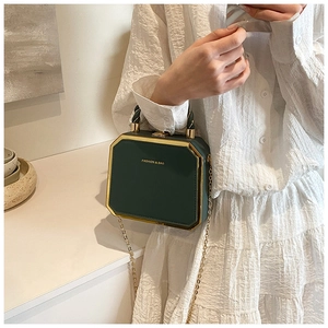 Detail shot of a dark green octagonal PU leather chain bag with gold metal trim