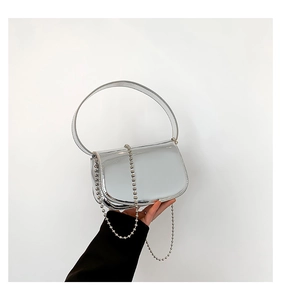 Detail of silver mirror patent leather handbag featuring metallic beaded chain decoration