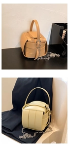 Detailansicht der gewebten Würfel-Eimertasche mit matten Lederriemen und Ketten-Schultergurt
