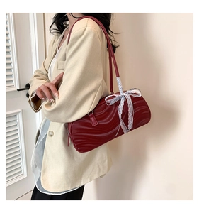 Detail of burgundy shoulder bag with 3D wave texture and white lace bow accessory