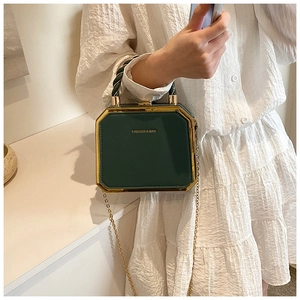 Detail of a dark green octagonal box bag with gold metal frame and chain strap