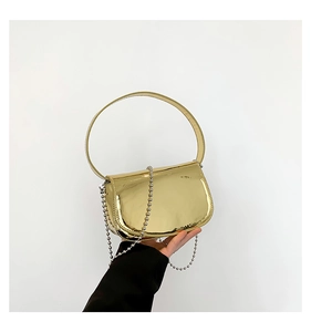Close-up of shiny gold patent leather saddle bag with decorative silver metal bead chain strap
