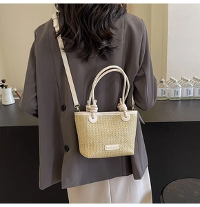 Close-up of straw bucket bag with leather trim and Fashion & Bags metallic plaque logo