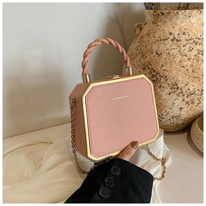 Macro view of pink octagonal box bag with gold metal trim and unique twisted handle