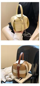 Nahaufnahme gewebter Leder-Eimertaschen mit Metallketten im modernen, minimalistischen Design