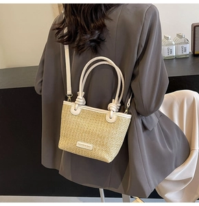 Detailed shot of straw tote with white leather handles and fashion leather tag