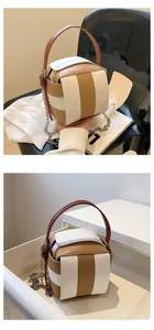 Makro-Detail der würfelförmigen Umhängetasche aus Leder mit braun-weißem Farbblock-Design