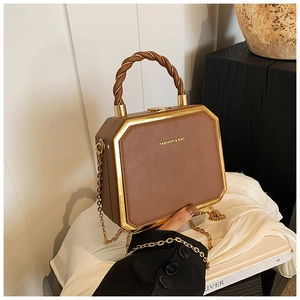 Detail of a brown octagonal box bag featuring golden metal frame and chain strap