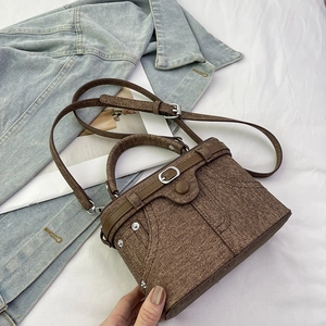 Detailed view of brown textured crossbody bag with denim-inspired pockets and rivets