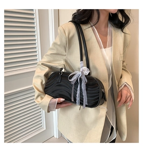 Detail of black textured handbag with black and white plaid bow on the shoulder strap