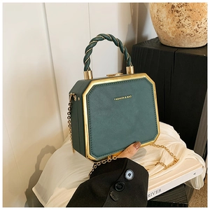Detail of dark green octagonal box bag with gold trim and braided handle detail