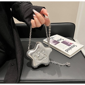 Macro view of silver star-shaped chain bag with embossed smiley face on leather seat