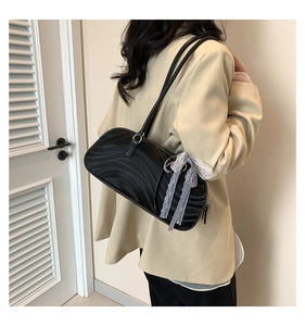 Detail view of black bow shoulder bag with textured surface and ribbon decoration