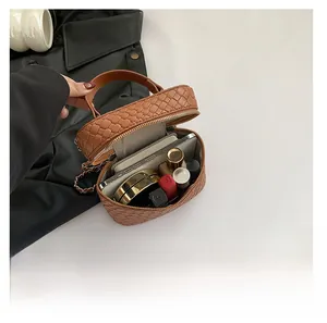Dettaglio della capacità interna della borsa intrecciata marrone con trucchi e cellulare