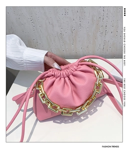 Detail of pink pleated bucket bag featuring thick gold chain and lychee grain leather