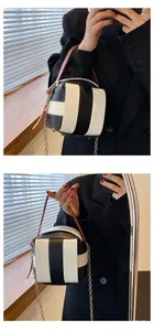 Detailansicht der gestreiften Eimertasche mit braunem Ledergriff und silberner Metallkette