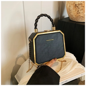 Detail of black pebbled leather box bag with gold metal trim and woven handle texture