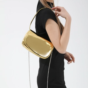 Glossy gold patent leather shoulder bag with metal finish and dual straps on model
