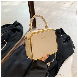 Detail of octagonal cream box bag with gold metal trim and woven handle on black blazer