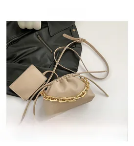Detail view of beige pouch bag with gold chain handle and matching mini card wallet