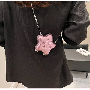 Detail of pink star-shaped metallic crossbody bag with chain strap on a model