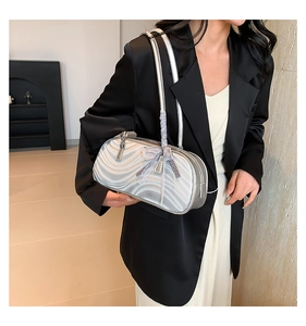 Detail of silver pillow bag with wave texture and checkered bow ribbon on shoulder strap