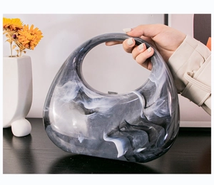 Detailed shot of marble pattern acrylic handbag with integrated handle and metal clasp