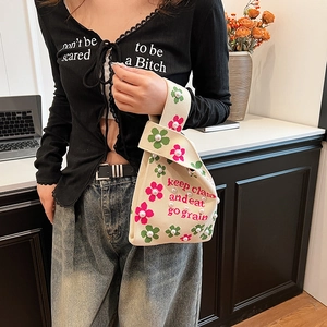 Knitted bucket bag with floral embroidery and pearls shown in a lifestyle setting