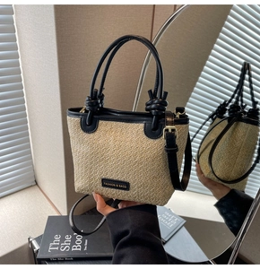 Detail of straw bucket bag with black leather trim, knotted handle and metal buckles