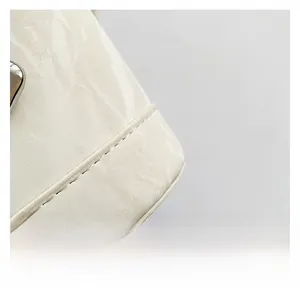 Macro view of premium beige leather texture and precise stitching on a chic bucket bag