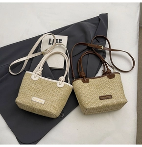 Detail of large straw tote bags with leather trim and fashion brand plate on casual bedding
